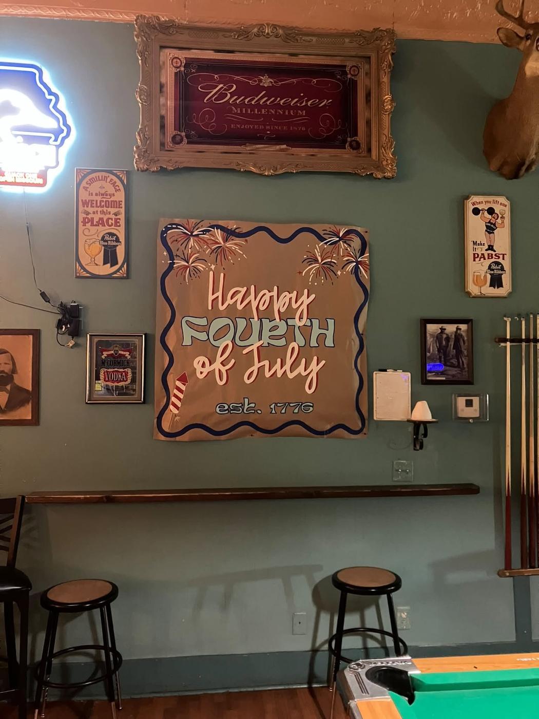 Inside the bar: teal walls, a neon Missouri sign, bar stools, a cue rack and the pool table
